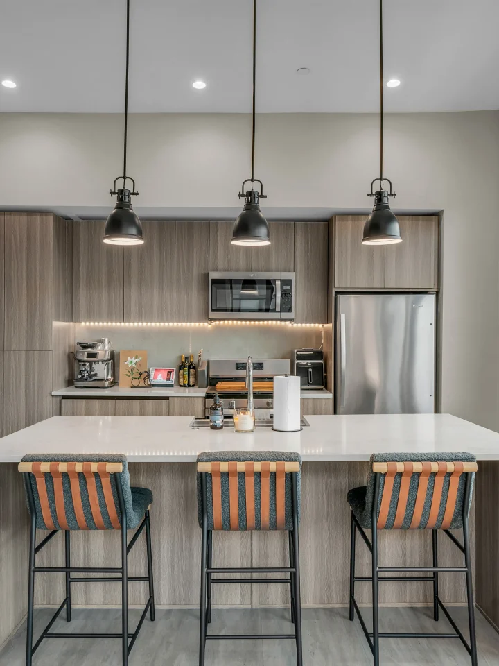 Modern apartment kitchen with stools and pendant lights at Salt Lake Crossing.